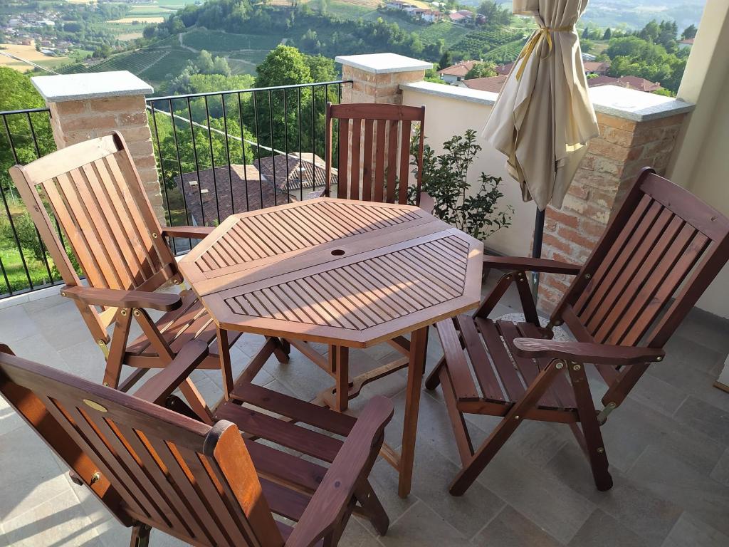 a wooden table and four chairs on a balcony at Casa Mantel Holiday Home Panoramic view in Langhe in Novello