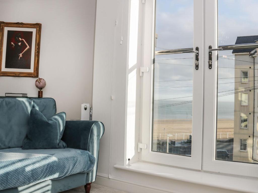 a living room with a blue couch and a window at Beach House in Rhos-on-Sea