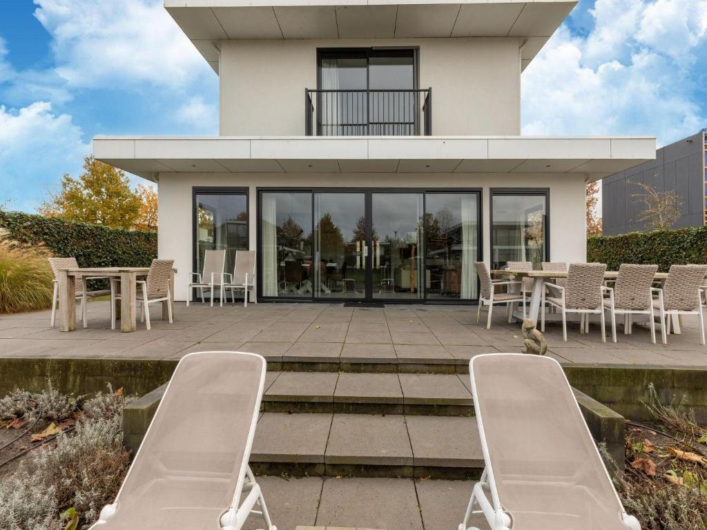 ハルデルウェイクにあるModern Villa with bubble bath Sauna in Harderwijk Flevolandのパティオ(椅子、テーブル付)が備わる家