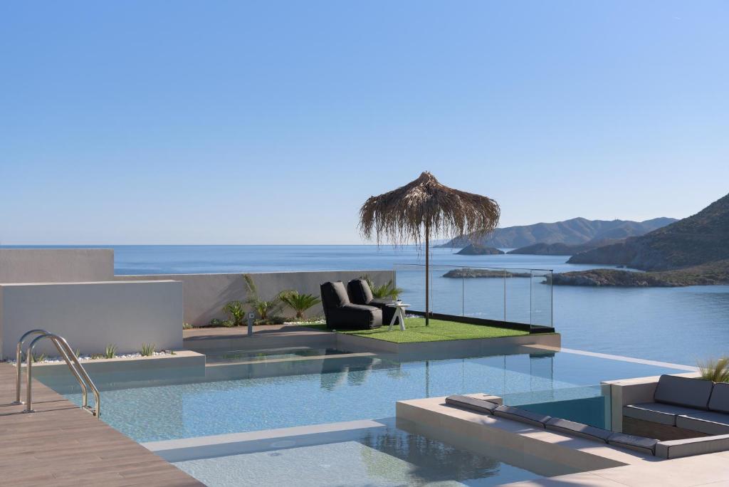 basen z 2 krzesłami i parasolem w obiekcie Mayana Luxury Villa, an infinite blue experience, by ThinkVilla w mieście Balíon
