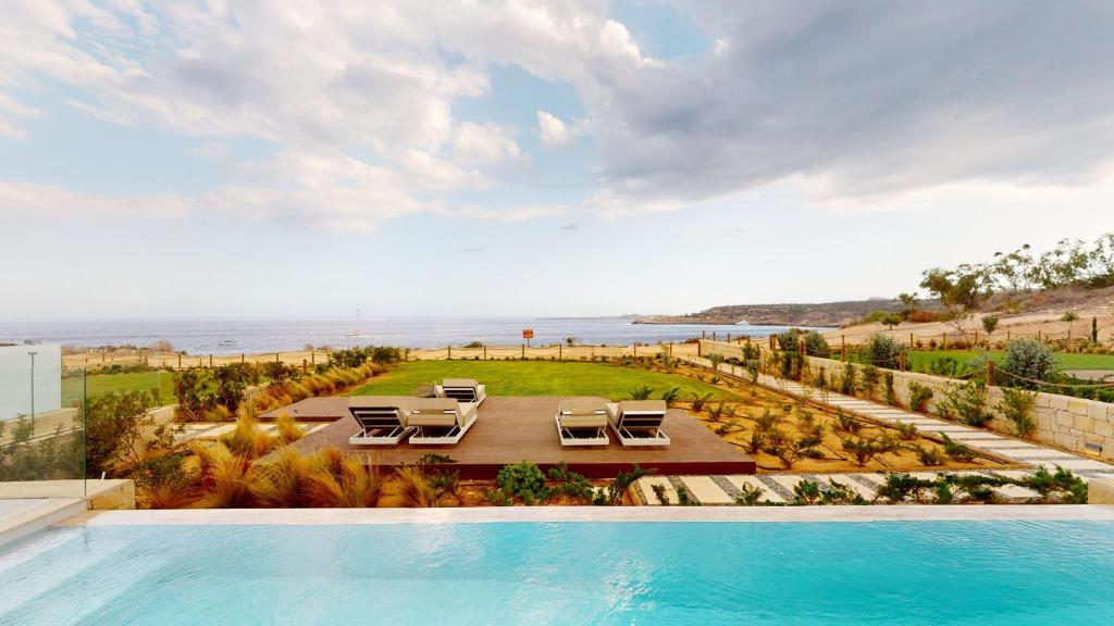 a pool with chairs and a view of the ocean at Periyiali Konnos Villas Beach Resort in Protaras