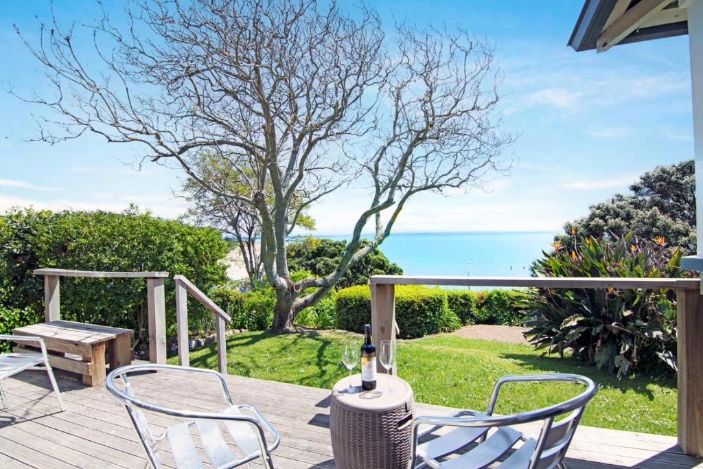 a patio with a table and two chairs and the ocean at Bayview Bungalow - Nelson Holiday Home in Nelson