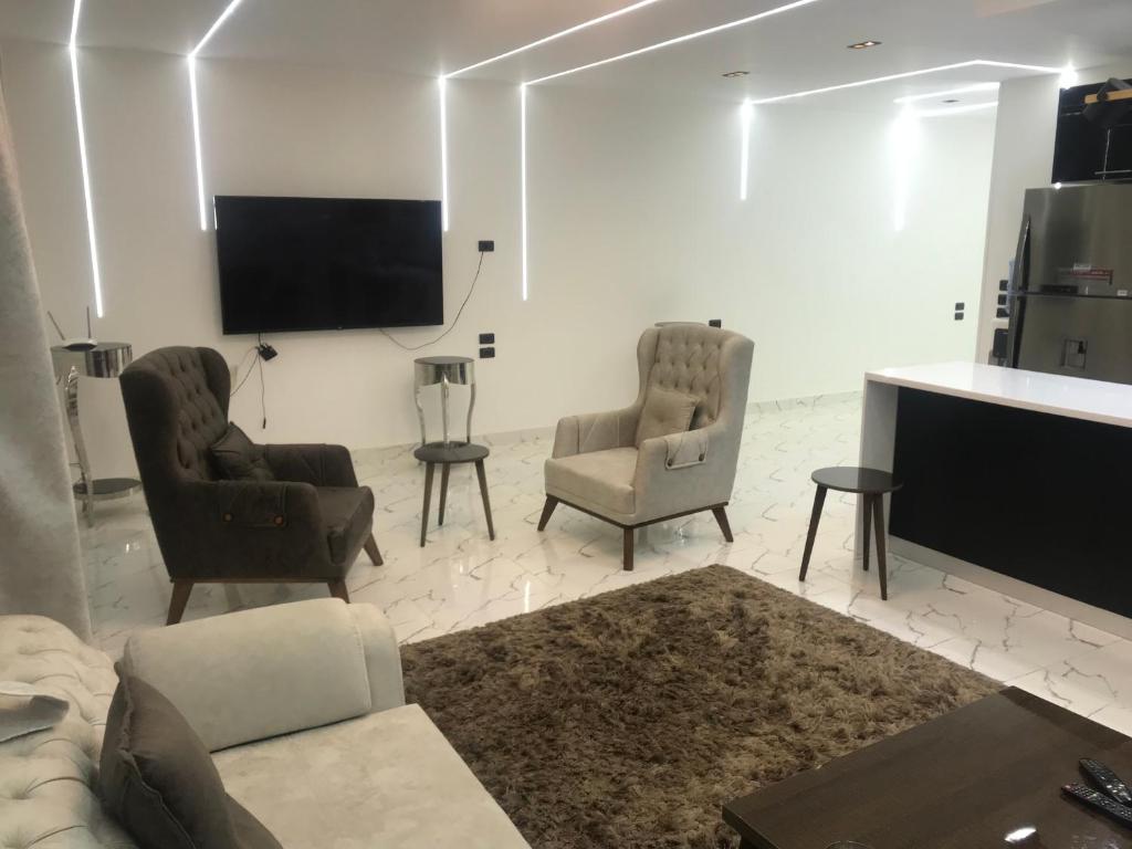 a living room with two chairs and a flat screen tv at شقة فندقية بغرفتين قرب مول مصر وميدان جهينة families only in Sheikh Zayed