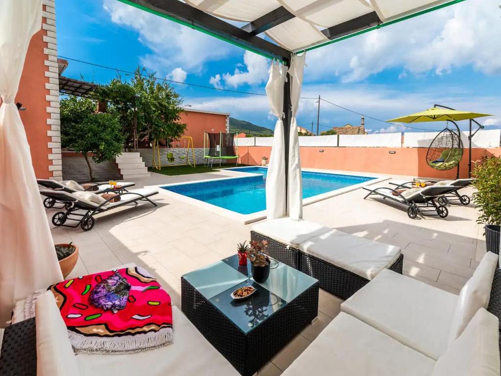 un patio con piscina, sillas y mesa en Apartment Dionis Domus, en Vela Luka