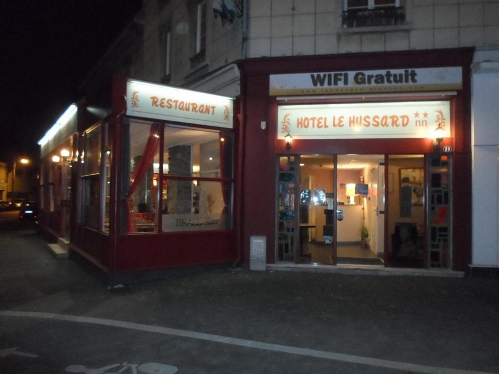 Quelques fronts de magasins dans une rue la nuit dans l'établissement Hôtel Le Hussard, à Aleçon