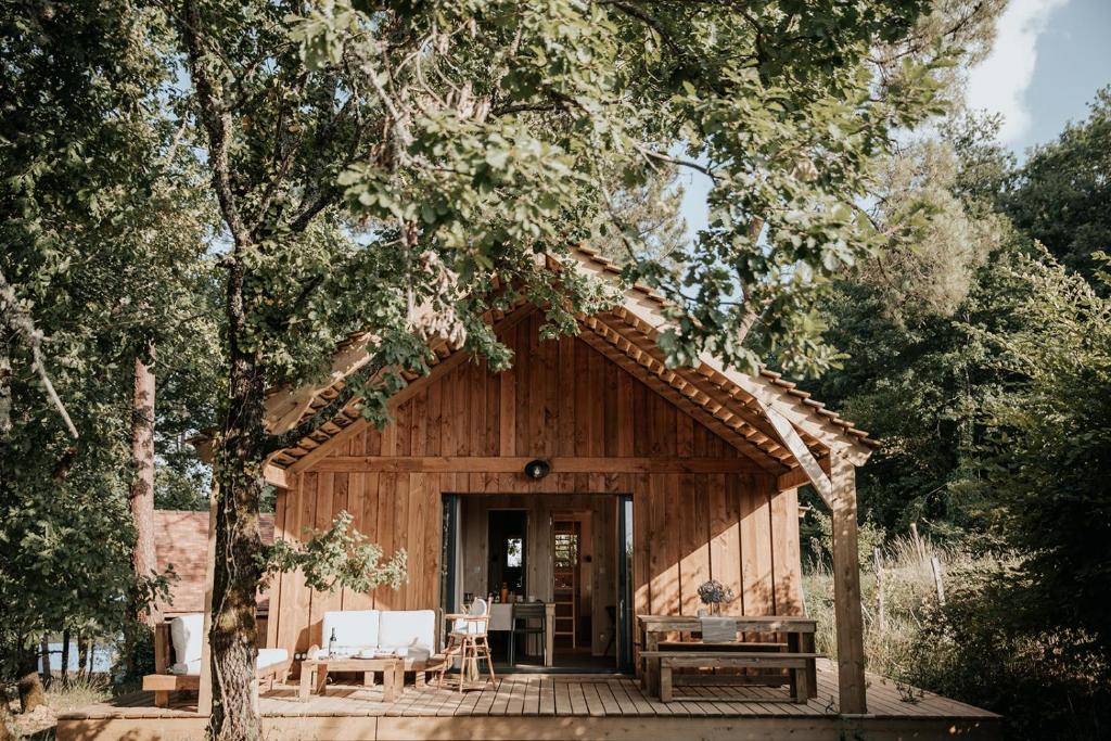 een houten hut met een tafel en stoelen ervoor bij Domaine St-Amand in Saint-Amand-de-Coly