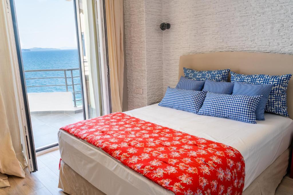 Schlafzimmer mit einem Bett mit blauen und roten Kissen in der Unterkunft Limani Luxury Apartments Beachfront in Sarandë