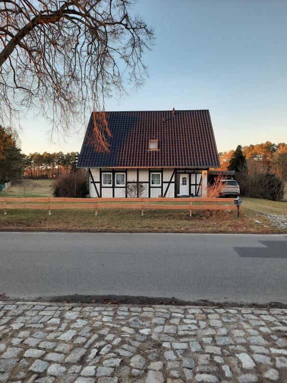 a house with a black roof on the side of a road at Haus Maria in Ahlbeck