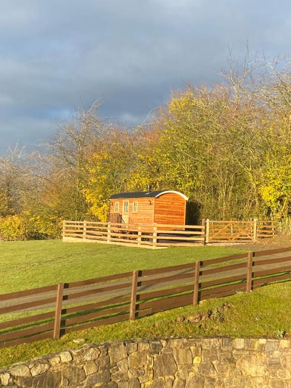 a wooden house in a field next to a fence at The Snug at Coed Y Gaer in Oswestry