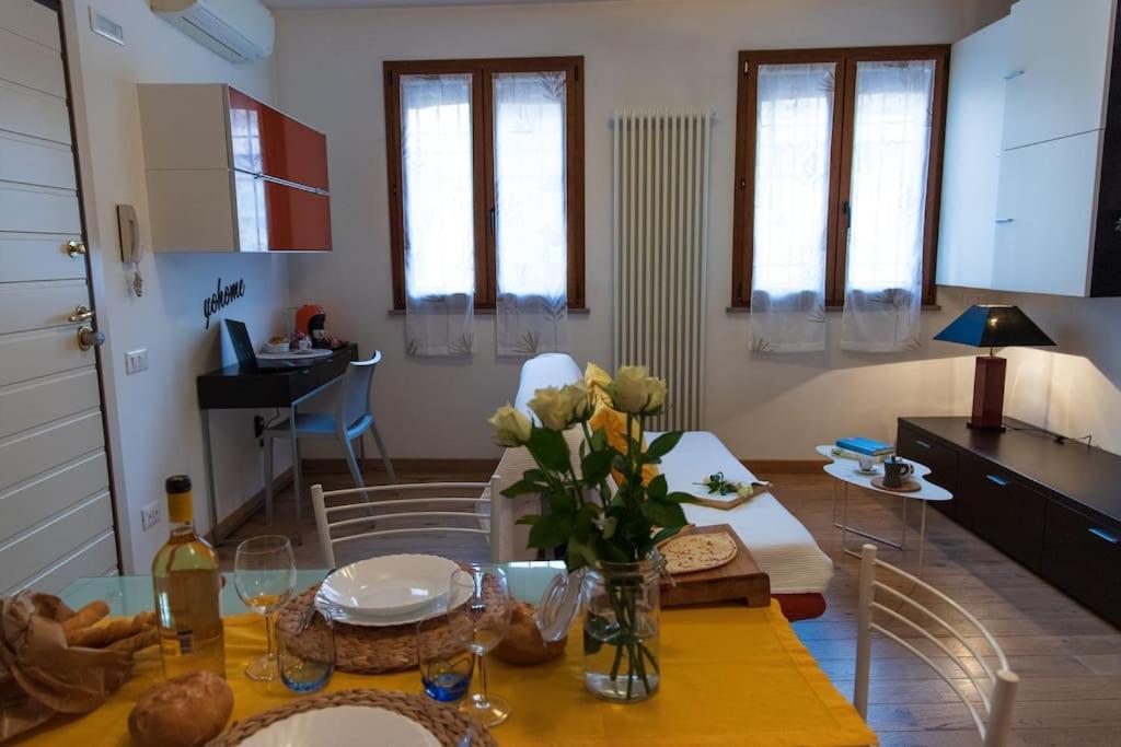 Pascoli Home a Cattolica Centro Mare by Yohome في كاتوليكا: مطبخ وغرفة معيشة مع طاولة عليها زهور