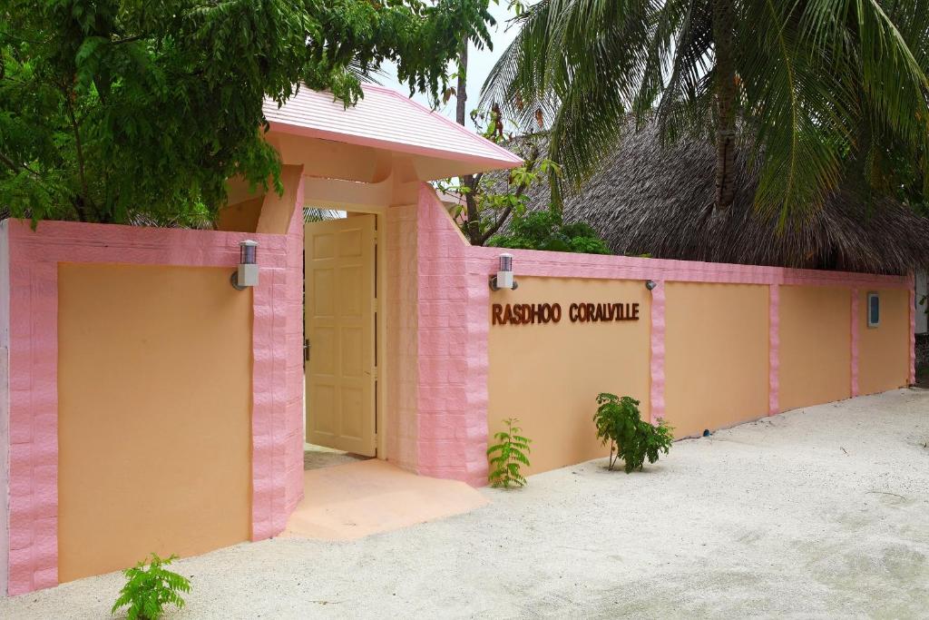 un edificio rosa con un letrero de canoa en el baño en Rasdhoo Coralville, en Rasdu