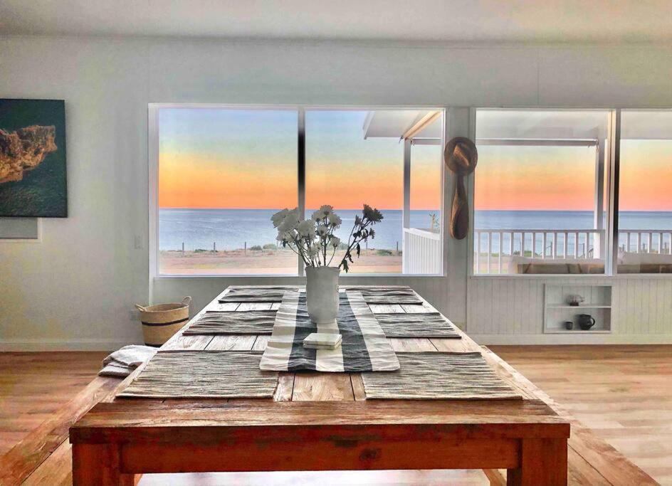 uma mesa num quarto com vista para a praia em The Landing Aldinga Beach Front Private Pool em Aldinga Beach