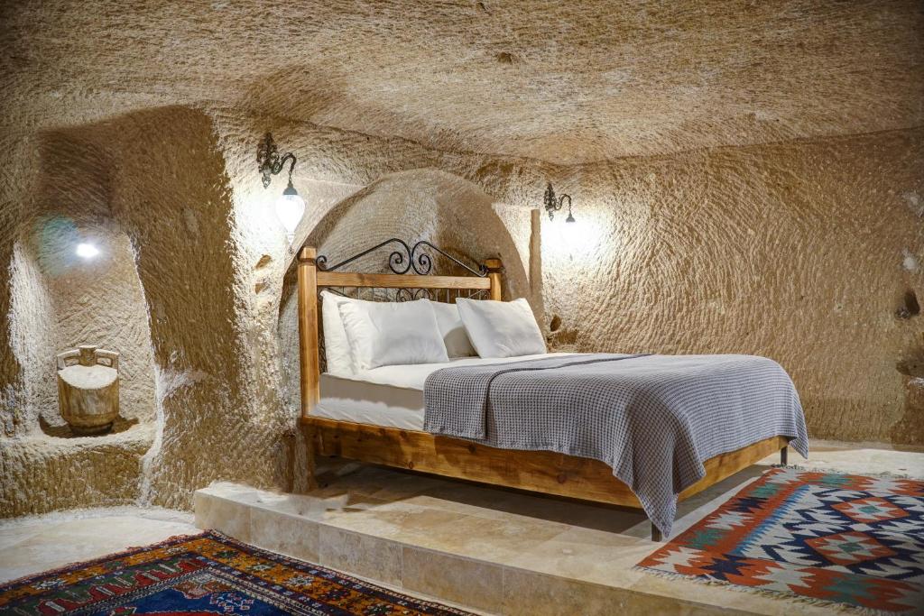 a bedroom with a bed in a stone wall at Karma Suites Cappadocia in Uchisar