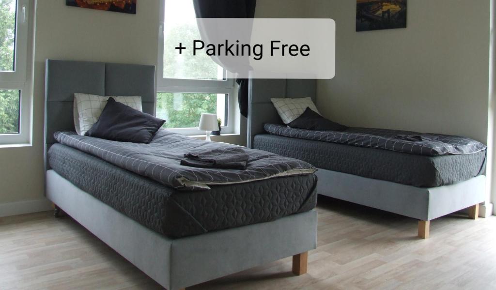 two beds in a bedroom with a sign that reads parking free at White Room Wrocław przy Wyspie Opatowickiej in Wrocław