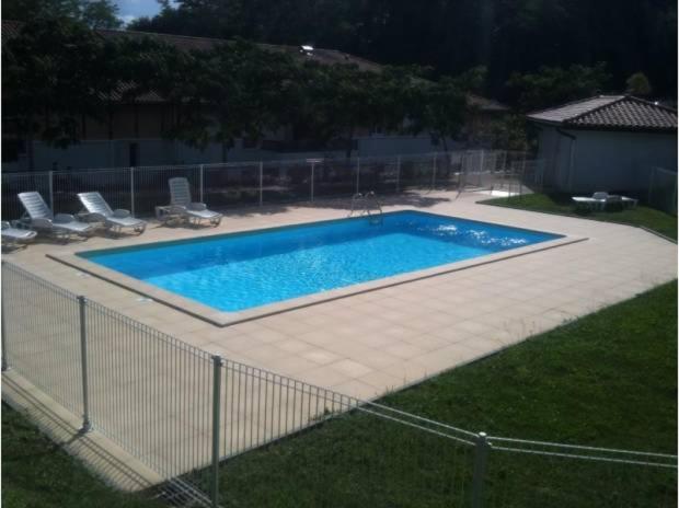 a swimming pool in a yard with chairs around it at SUPERBE APPART AVEC JARDIN ET PISCINE in Cambo-les-Bains