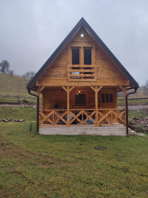 a large wooden cabin in a field of grass at Vikendica Jankovic in Pale