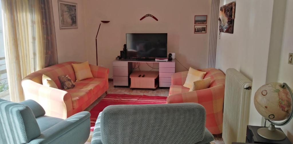 uma sala de estar com dois sofás e uma televisão em Ομορφο διαμερισμα με μεγαλες βεραντες em Atenas