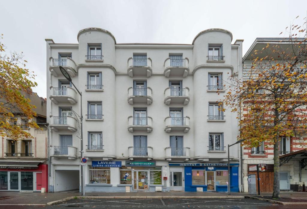 - un grand bâtiment blanc dans une rue de la ville dans l'établissement Résidence Celestins - Appartements centre avec parking, à Vichy