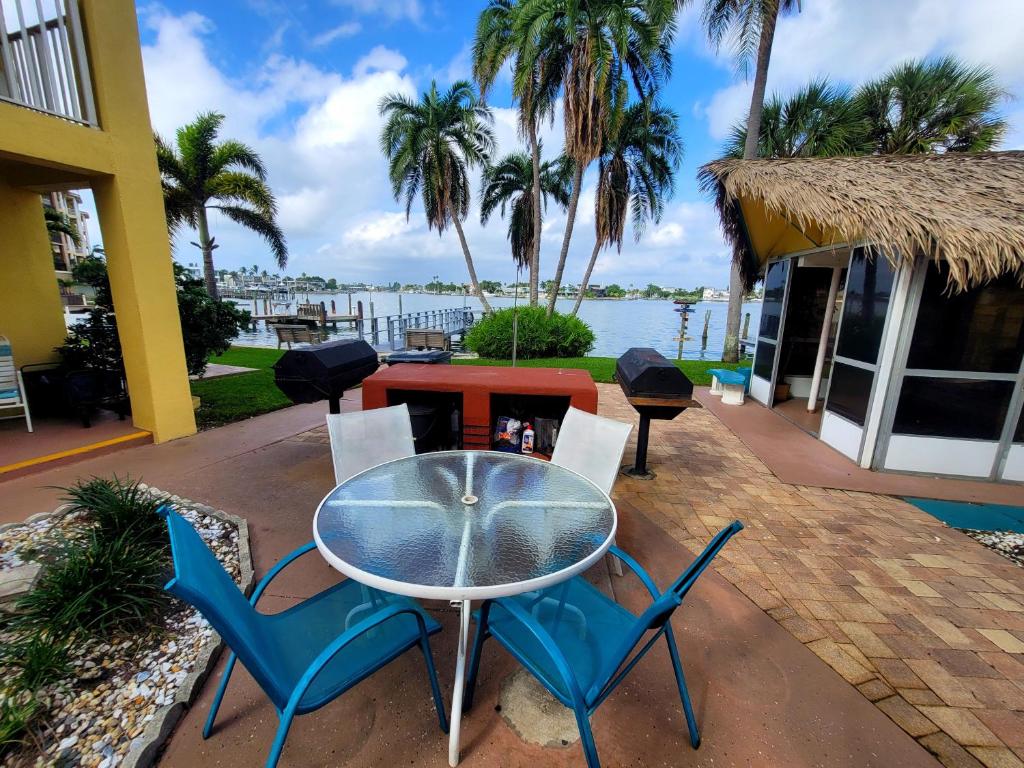 uma mesa de vidro e cadeiras num pátio com água em Searenity, Waterside studio in the heart of Treasure Island, walk to beach em St. Pete Beach