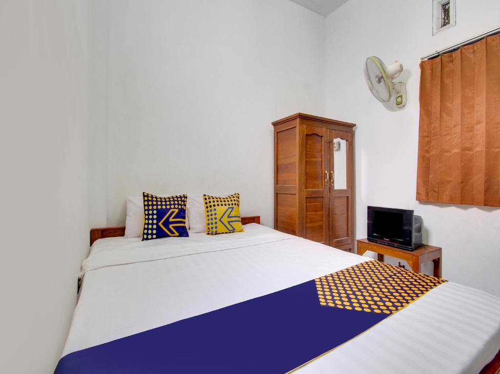 1 dormitorio con 2 camas y reloj en la pared en SPOT ON 91935 Hellena Guesthouse, en Demak