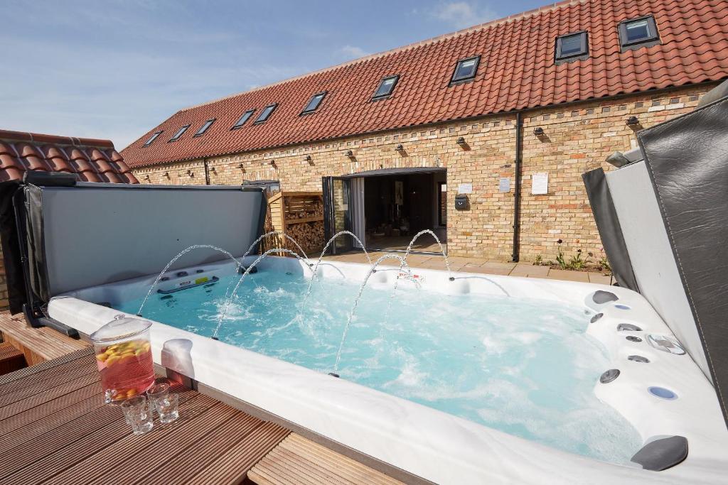 a hot tub on a deck with a building at Field Maple Barn, Ashlin Farm Barns in Lincoln