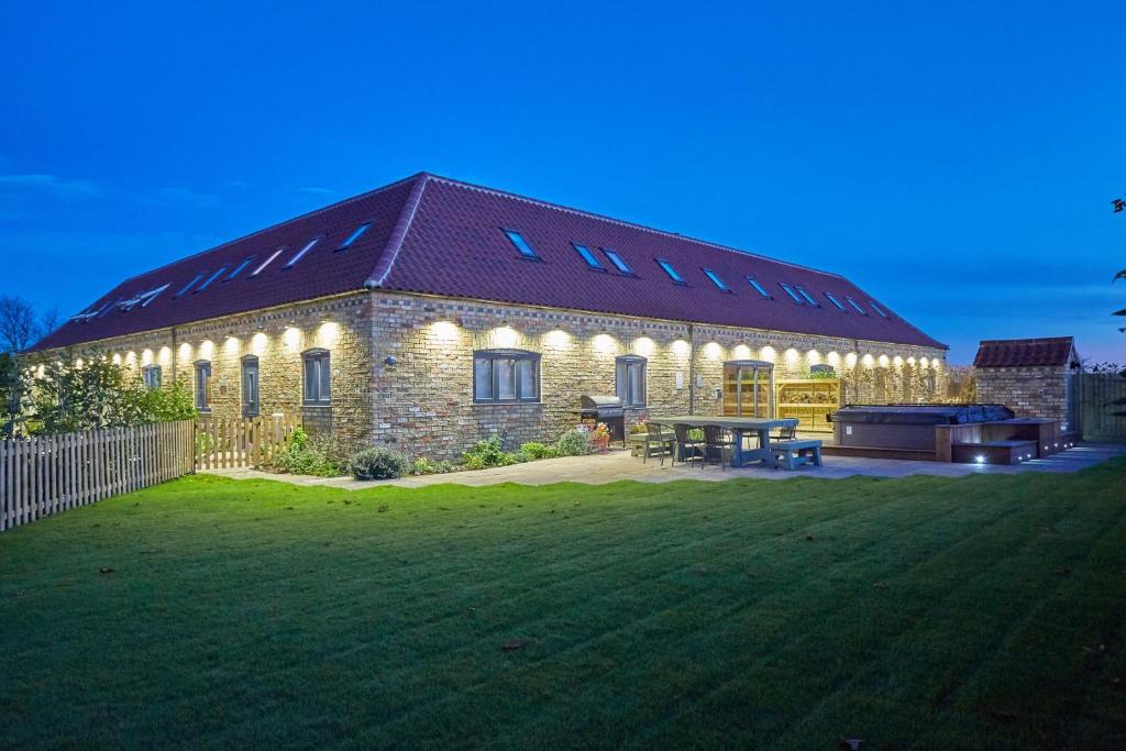 a brick house with lights on it in a yard at Red Oak Barn, Ashlin Farm Barns in Lincoln