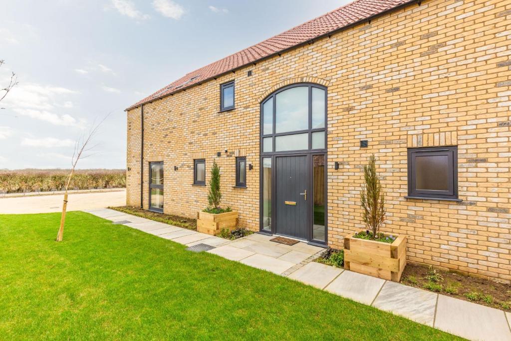 una casa in mattoni con una porta nera e due piante di The Willows, Ashlin Farm Barns a Lincoln