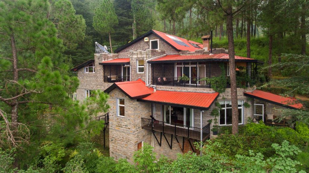 duży dom z czerwonymi dachami w lesie w obiekcie SaffronStays Ekam, Chail - forest villa near Chail cricket ground w mieście Shimla