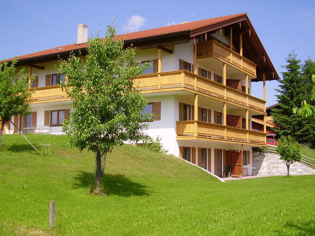 Un edificio su una collina con un albero davanti di Lindenhof Inzell - FeWo mit Chiemgaukarte a Inzell