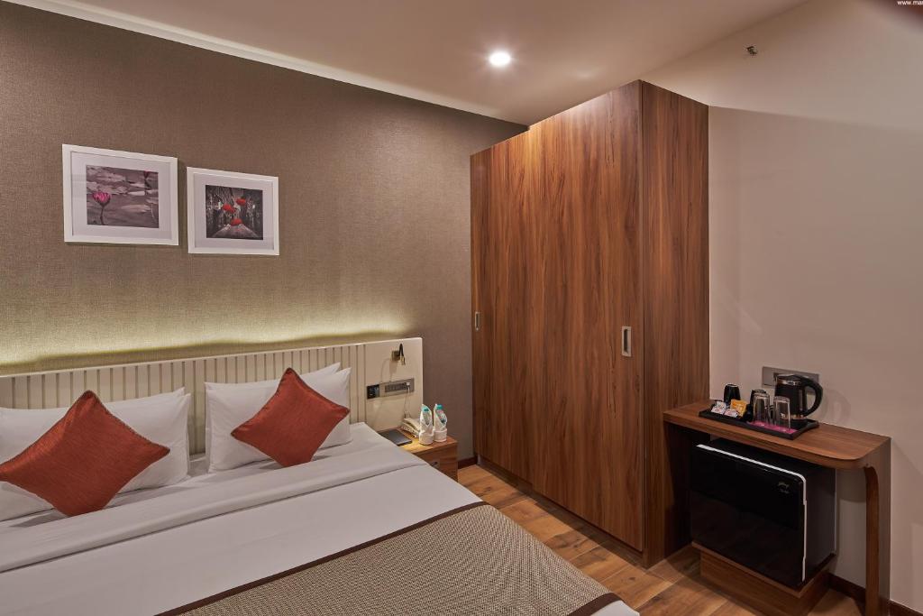 a bedroom with a large bed and a wooden cabinet at Regenta Inn Grand-ORR, Mahadevapura in Bangalore