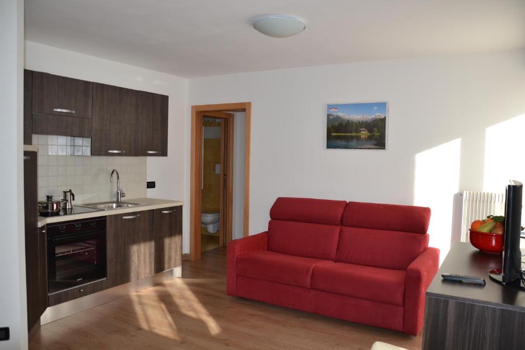 a living room with a red couch in a kitchen at Casa Olivati in Pellizzano