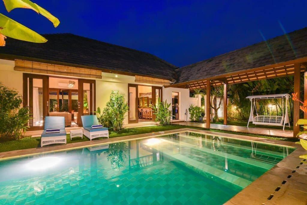 a villa with a swimming pool at night at Villa Intan in Legian