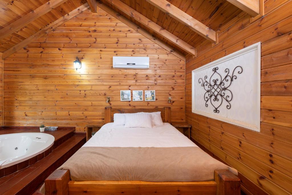 a bedroom with a bed and a tub in a wooden room at Nof Kineret Suites in Moshav Ramot