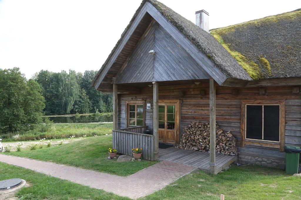 una cabaña de madera con porche y un montón de troncos en Sodyba šeimai "Obuolių namai", en Gaylyunay