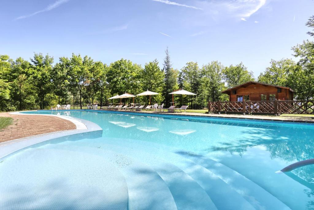 a large swimming pool with chairs and umbrellas at La Collina dei Ciliegi in Brufa