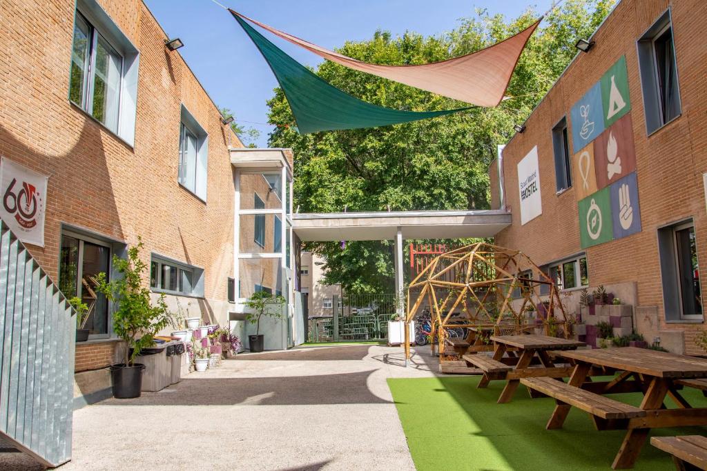 un patio con tavoli da picnic e una bandiera appesa tra due edifici di Scout Madrid Hostel a Madrid