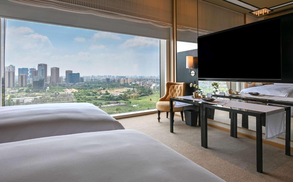 グルガオンにあるGrand Hyatt Gurgaonのベッド2台と大きな窓が備わるホテルルームです。