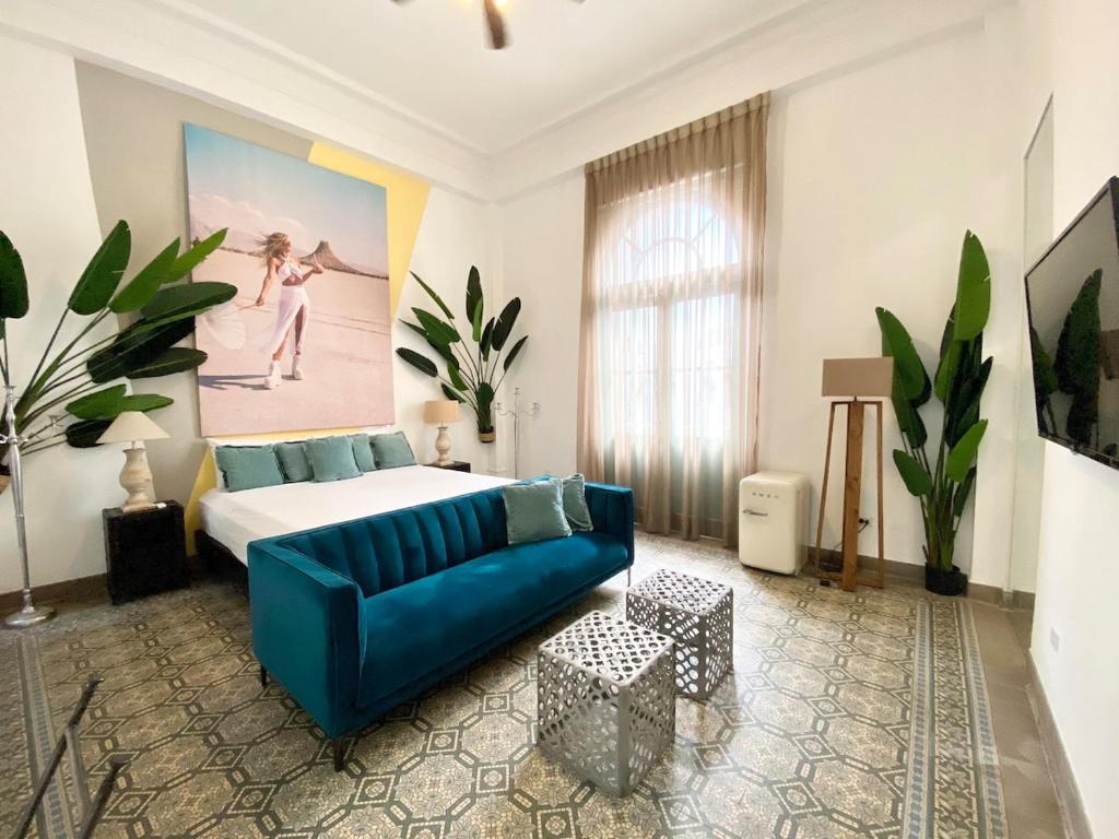 een woonkamer met een bed en een blauwe bank bij AmazINN Places Casco Viejo Pool and Rooftop VIII in Panama-Stad