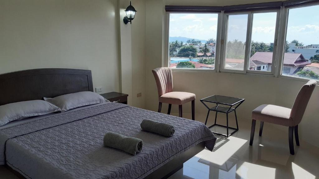 1 dormitorio con 1 cama, 2 sillas y ventanas en Avana Hills Boracay Prime Panoramic Suite, en Boracay