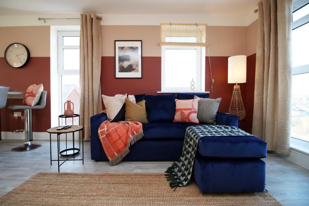 a living room with a blue couch with pillows at Stylish modern retreat overlooking Poole Quay in Poole