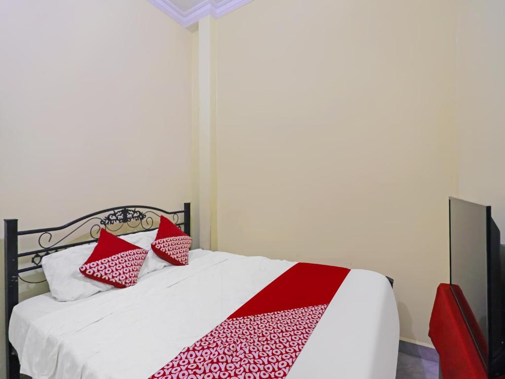 a bedroom with a bed with red and white pillows at OYO 91974 Alfisal Syariah in Bagam