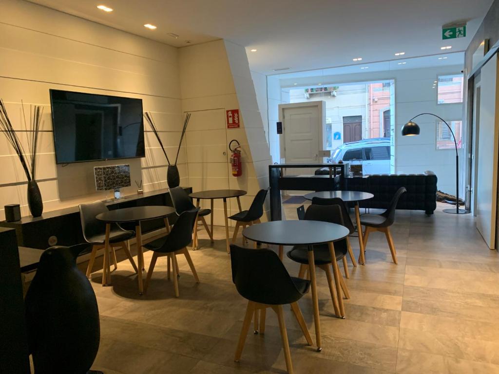 a restaurant with tables and chairs and a tv at Neko Boutique Hotel in Cagliari