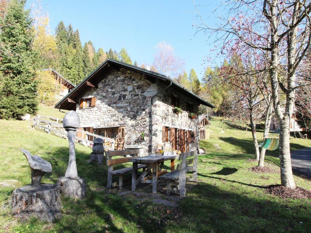 een stenen huis met een picknicktafel ervoor bij Wooden chalet in Pieve Tesino with garden in Pieve Tesino