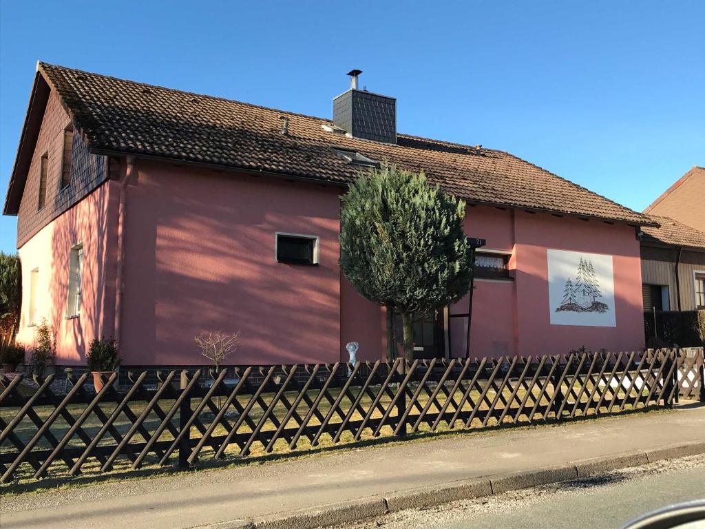 um edifício vermelho com uma cerca em frente em Privatvermietung Ina em Buntenbock