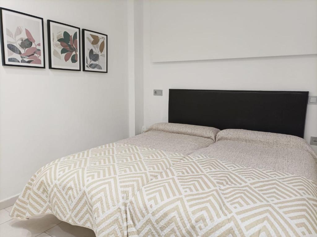 1 dormitorio blanco con 1 cama y 3 cuadros en la pared en Apartamento Bajo 3 Dúplex Marjal playa centro de Guardamar, en Guardamar del Segura