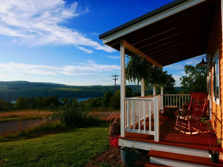 un porche de una casa con dos sillas en Vineyard Farmhouse with Hot Tub & Lake Views en Hammondsport