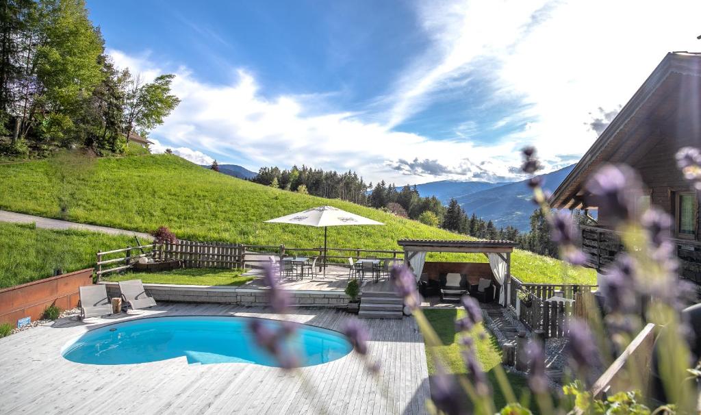 a swimming pool with a table and an umbrella at Residence Alpenrose in Bressanone