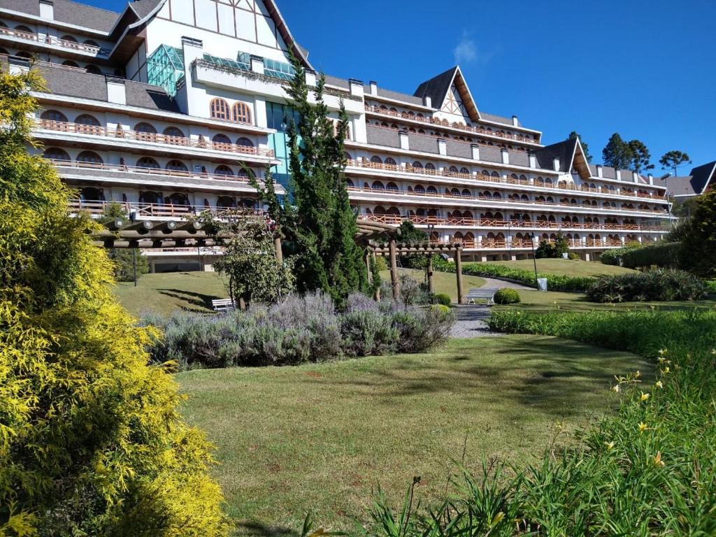 un gran hotel con un jardín delante de él en Flat Quatre Saisons - Apartamento em Campos do Jordão, en Campos do Jordão