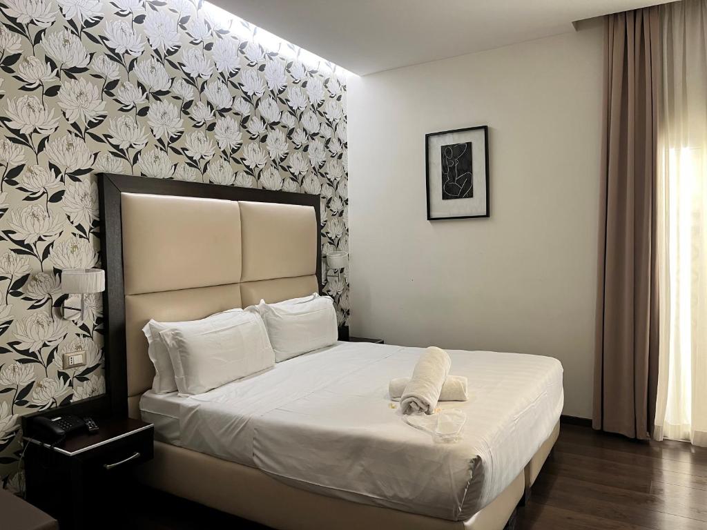 a bedroom with a large white bed with a wall at Catone District Hotel in Rome