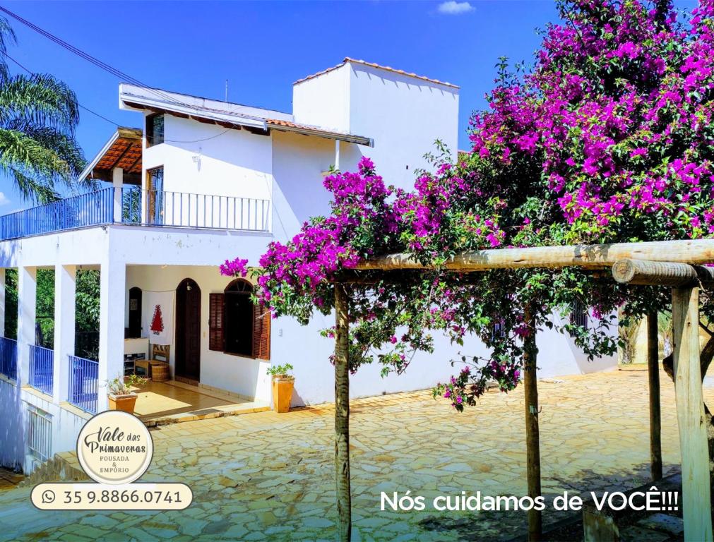 une villa avec des bougainvilliers violets en face d'une maison dans l'établissement Pousada Vale das Primaveras, à Três Corações